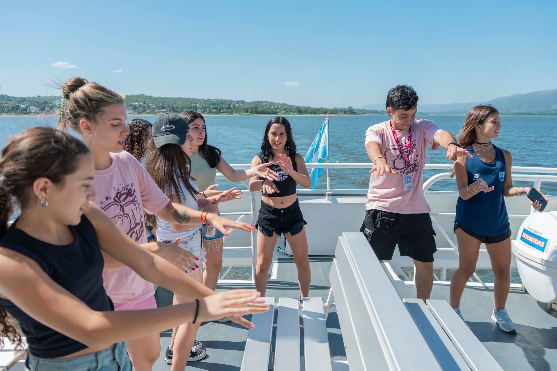 Grupo de egresados bailando en la cubierta del catamarán durante el paseo por el lago