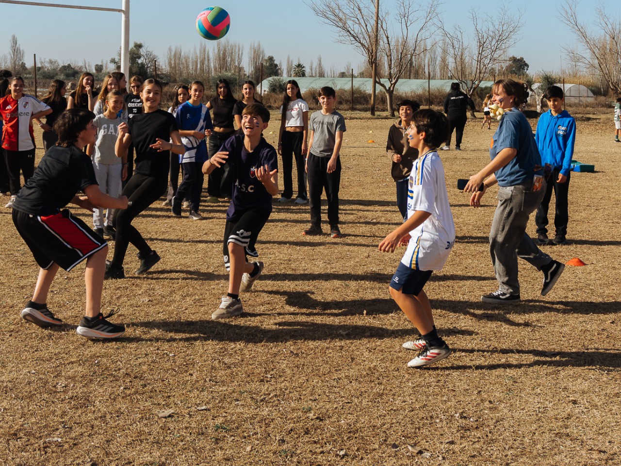 Grupo de jóvenes jugando con una pelota en una cancha al aire libre