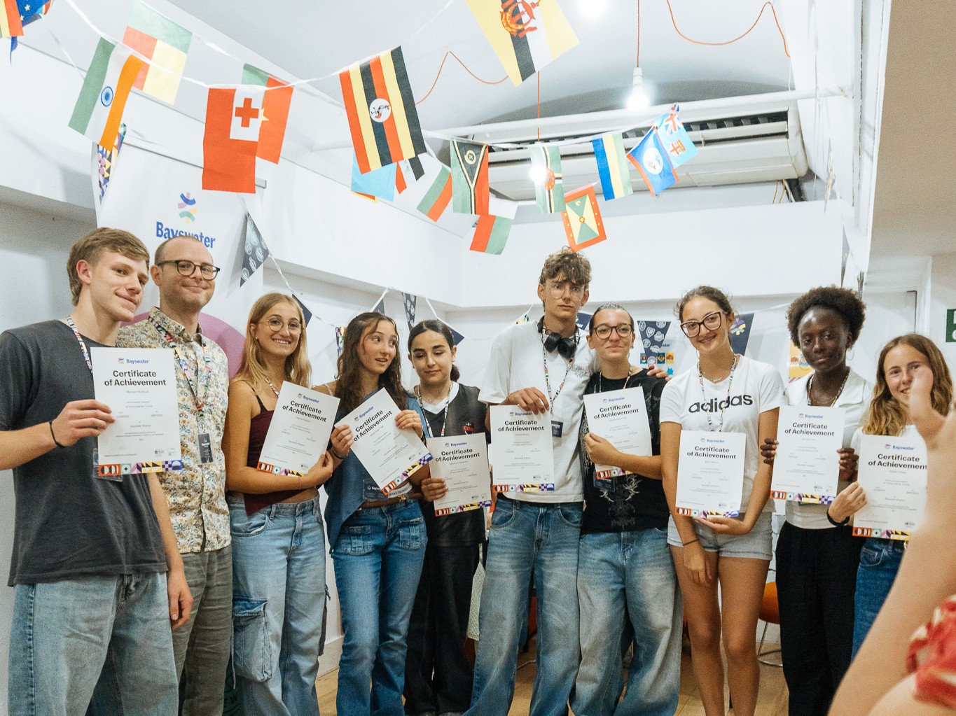 Grupo de estudiantes mostrando sus diplomas junto al profesor al finalizar el curso de inglés