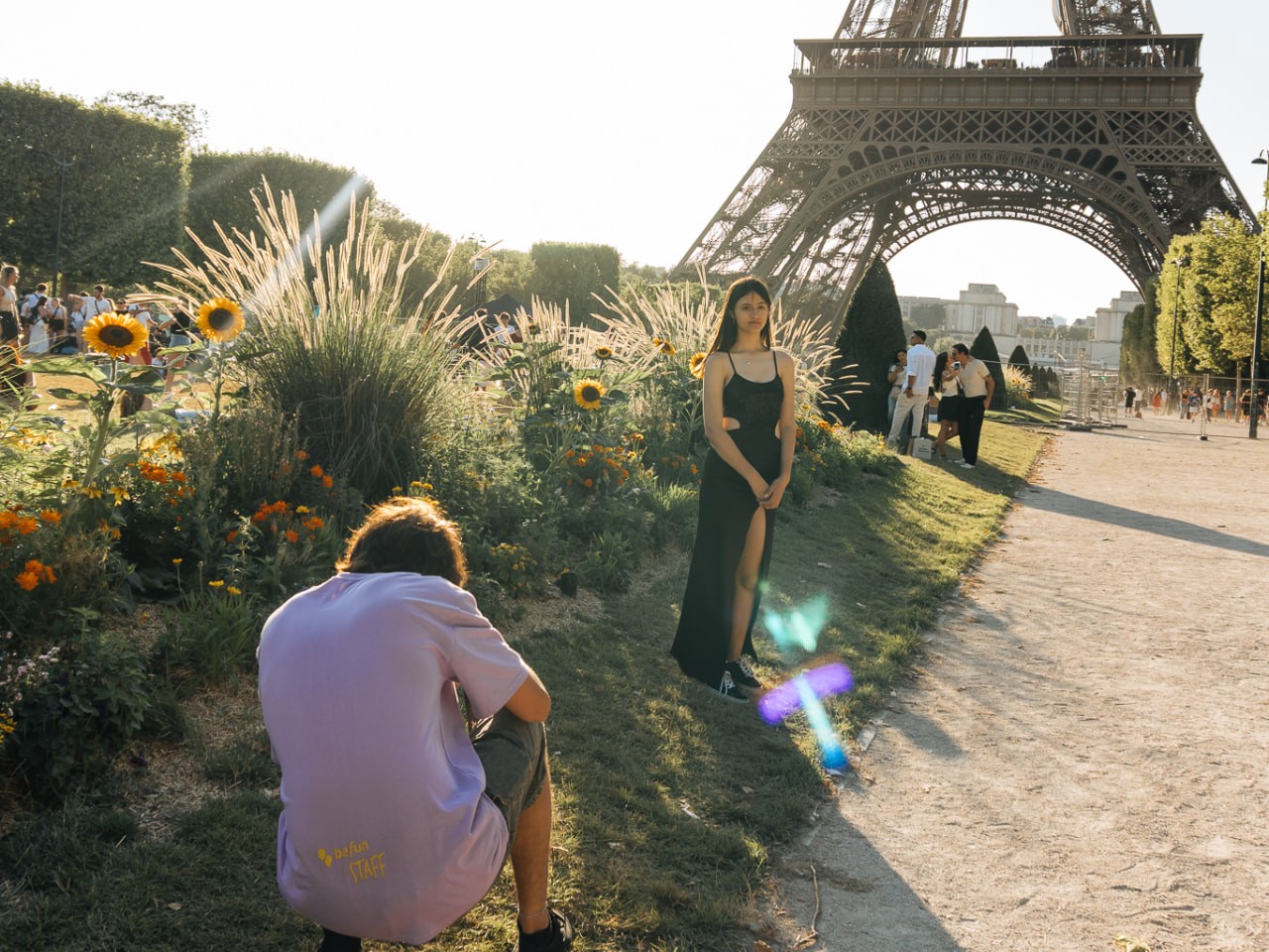 Joven posa junto a un cantero de girasoles con la Torre Eiffel al fondo mientras un integrante del staff la fotografía